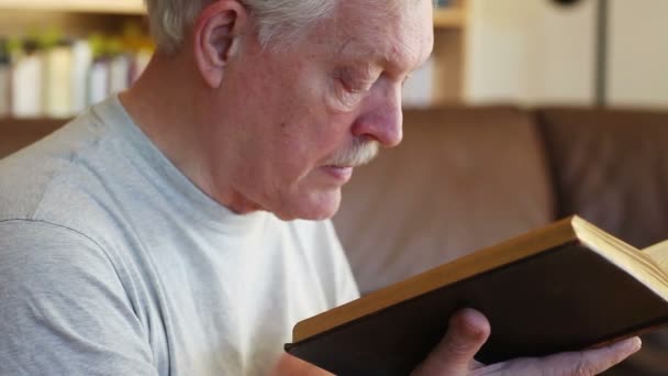 Homme Âgé Lit Sur Canapé Devant Une Bibliothèque — Video