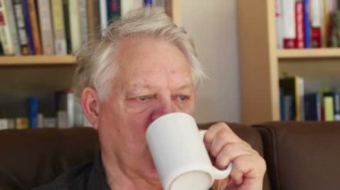 Oturma odasında kahve içen kıdemli adam