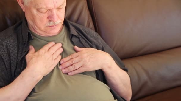 着席した年配の男性は テキストのための部屋で彼の胸に痛みと圧力を経験します — ストック動画