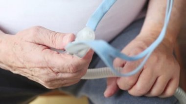 Kıdemli bir adam Cpap makinesinin başlık kısmına bakıyor.