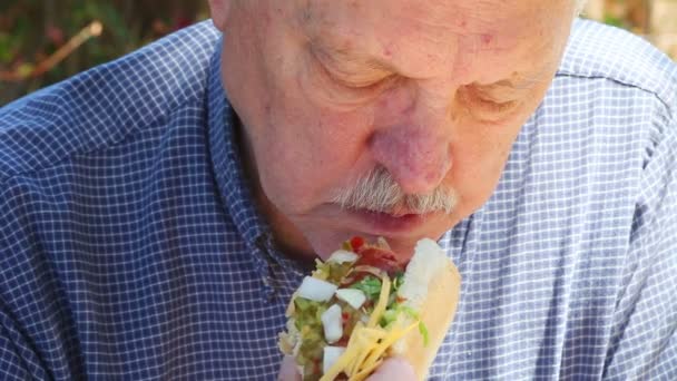 Senior Man Eet Een Hotdog Met Spek Geraspte Kaas Gehakte — Stockvideo