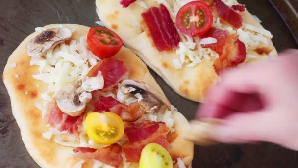 Frau Macht Naan Pizzen Mit Kirschtomaten Mozzarella Pilzen Und Speck — Stockvideo