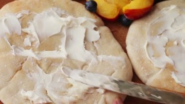 Naan ekmek üzerinde mascarpone peyniri serpme ve taze şeftali dilimleri ve yaban mersini ufalanmış feta serpilir ekleyerek