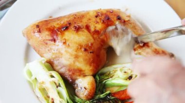 Bir kadın sebze ile bir tabakta tavuk bir parça keser