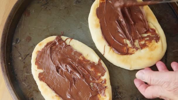 Een Vrouw Zet Chocoladepasta Witte Melkchocolade Chips Marshmallows Kleine Pizza — Stockvideo