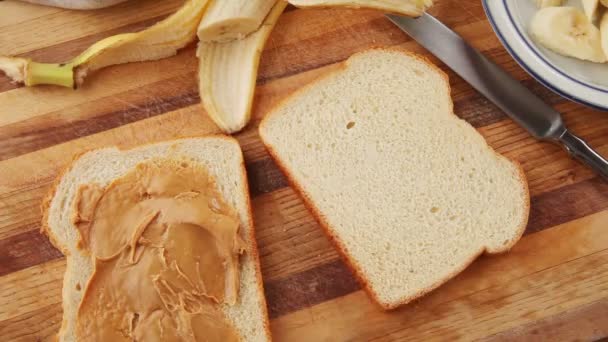 Женщина Разбрасывает Арахисовое Масло Шоколад Хлеб Затем Добавляет Нарезанные Бананы — стоковое видео