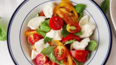 Bir kadın aşçı bitirmek için karabiber ve fesleğen yaprakları ekleyerek, caprese salatası hazırlar
