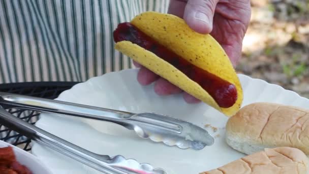 屋外の料理人は タコスシェルにフランクフルトを入れ チリと刻んだ生の玉ねぎを追加します — ストック動画