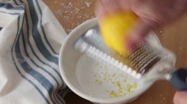 Bir mikrouçak kullanarak, bir kadın narenciye krema yapmak için pudra şekeri bir kase üzerinde limon kabuğu ızgara