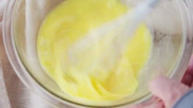 Bir kadın bir cam karıştırma kase yumurta dövmek için bir çırpıcı kullanır