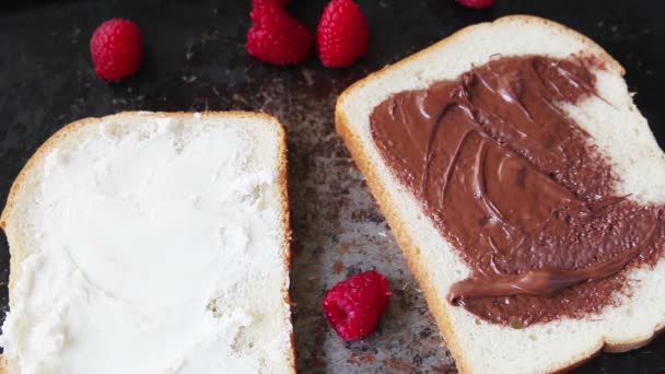 Een Vrouw Zet Chocolade Hazelnootpasta Verse Frambozen Wit Brood — Stockvideo