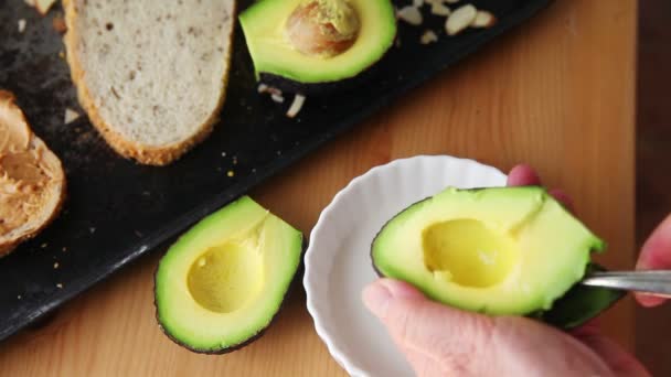 Woman Uses Spoon Scoop Out Avocado Flesh — Stock Video
