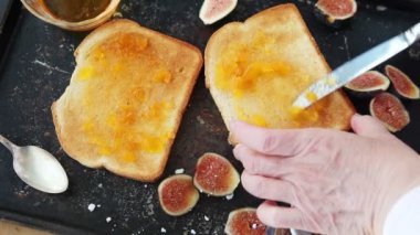 Bir kadın tost dilimleri için şeftali reçeli ve incir ekler