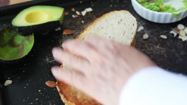 Kvinna Skär Jordnötssmör Och Avokado Smörgås Tredjedelar Och Staplar Bitarna — Stockvideo