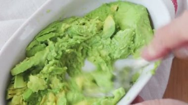 Bir kadın bir avokado mashes ve limon suyu ekler