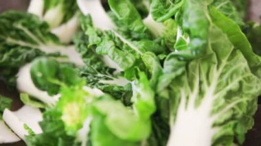 Bir wok taze Asya yeşillikleri büyük miktarda pişirme, bir metal spatula kullanarak