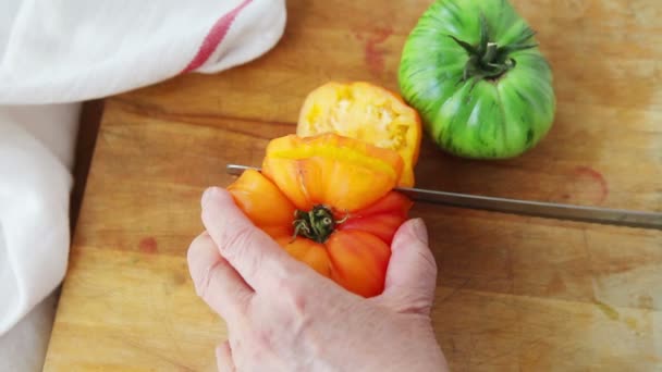 Uma Mulher Corta Dois Tomates Herdeiros Coloridos — Vídeo de Stock