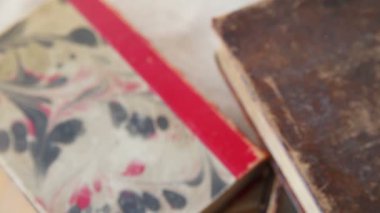 Bir kadın eski kitapları istifler, mermer bir tasarıma sahip eski bir kitapla biten