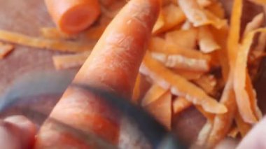 Bir kadın havuç ları yakından soyuyor.