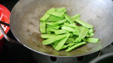 Bir kadın taze kar bezelye pişirmek için bir wok spatula kullanır