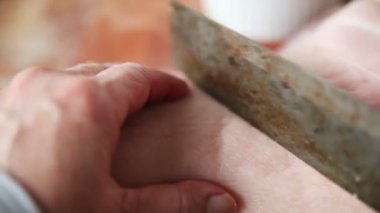 Bir kadın kavurmadan önce domuz göbeğinin sert derisini keser.