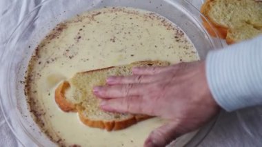 Bir kadın yumurta ve tarçın ile harmanlanmış süt içine ekmek ıslatır