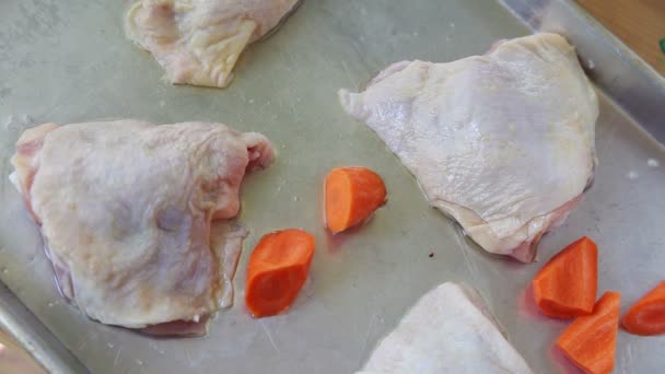 一个女人把卷心菜和胡萝卜放在一张有鸡大腿的平底锅餐上 — 图库视频影像