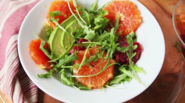 Bir kadın avokado ve bebek yeşillikleri ile taze narenciye salatası yapar