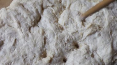 Bir kadın tahta bir kaşık sapı ile ekmek hamuru delik yapar