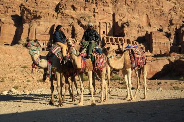Jordan, Petra, 5 Aralık 2016: Petra, başlangıçta Nabateans için Raqmu - Ürdün tarihi ve arkeolojik kent olarak bilinen kral mezarları Ürdünlü develer üzerinde yakın. İpek ve Urn mezarları adam üstünde