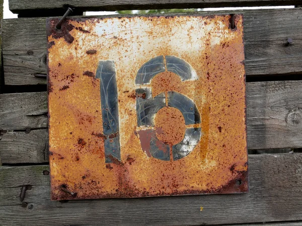 Antiguo número vintage dieciséis placa de la puerta en la cerca de madera vieja — Foto de Stock