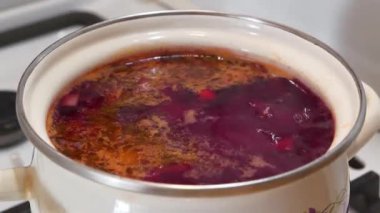 Ukrayna borsası gaz sobasında pişirilir. Ukrayna 'nın ulusal yemeği. Ukrayna mutfağının ana yemeği. İlk yemekleri pişiriyorum. Kırmızı Ukrayna çorbası beyaz tencerede kaynıyor.