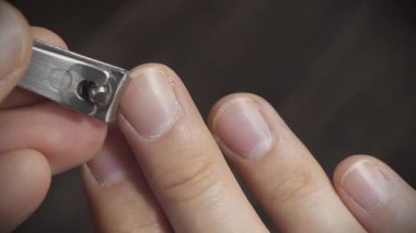 Tırnak makasıyla tırnak kesen bir adam, yakın çekim videosu. Adam orta tırnağını kesiyor.