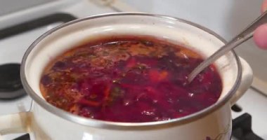 Ukrayna çorbası fırında pişirilir. Ukrayna 'nın ulusal yemeği. Ukrayna mutfağının ana yemeği. Aşçı çorbayı kaşıkla karıştırır. İlk yemekler. Kırmızı Ukrayna borsch 'u tencerede kaynıyor.