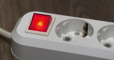 Güç adaptörü kırmızı enerjili ve göstergeli elektrikli portatif sokete yerleştiriliyor