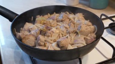 Kızarmış et. Aşçı et parçalarını fırında kızartılmış tavada soğanla karıştırır