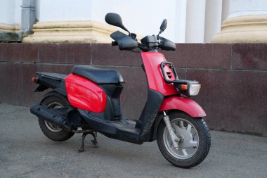 Binanın yakınında kırmızı ve siyah bir elektrikli scooter var.