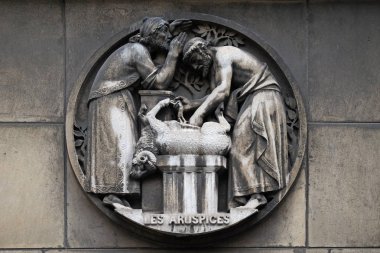 Aruspices, a priest in ancient Rome who practiced divination by the inspection of the entrails of animals. Stone relief at the building of the Faculte de Medicine Paris, France. clipart