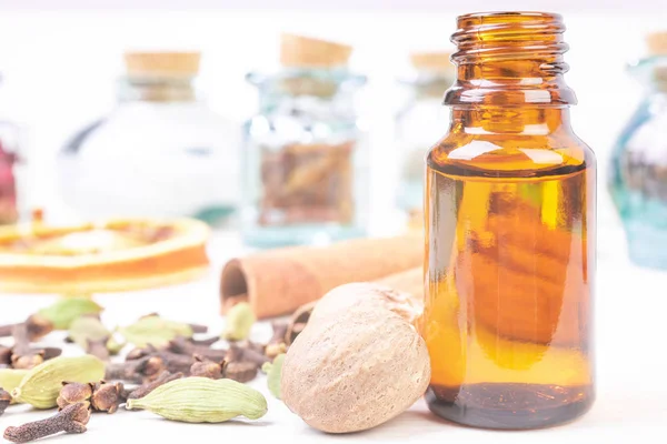 Essential oils in glass bottles maid from spices and nutmeg, cardamon, cinnamon, clove on wooden background