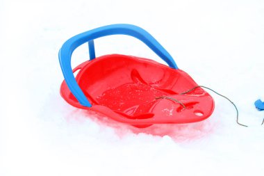 Kar arka plan üzerinde plastik kırmızı kızak