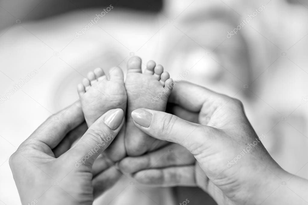 feet of the baby and hands of the parents black and white
