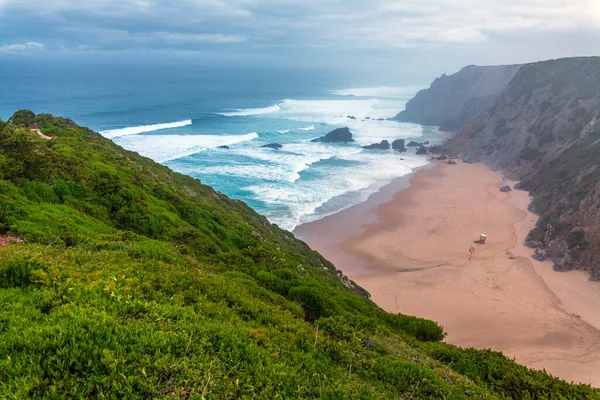 Beyaz binaları, terakotta çatısı, saksı bitkileri ve canlı çiçekleri olan sakin bir avlu berrak mavi gökyüzünün altında manzaralı bir okyanus manzarasına götürür.