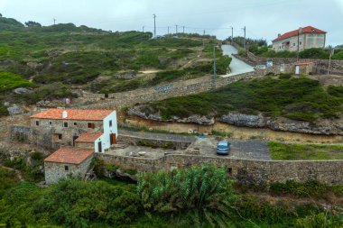 Sessiz bir kıyı yolu yemyeşil bitki örtüsü ve uzun kamışların arasından Atlantik Okyanusu 'ndaki açık mavi gökyüzünün altına doğru uzanır.