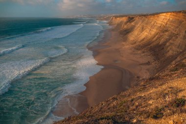 Sessiz bir kıyı yolu yemyeşil bitki örtüsü ve uzun kamışların arasından Atlantik Okyanusu 'ndaki açık mavi gökyüzünün altına doğru uzanır.