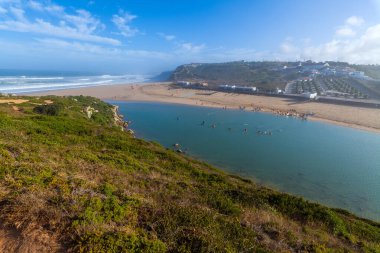 Sessiz bir kıyı yolu yemyeşil bitki örtüsü ve uzun kamışların arasından Atlantik Okyanusu 'ndaki açık mavi gökyüzünün altına doğru uzanır.