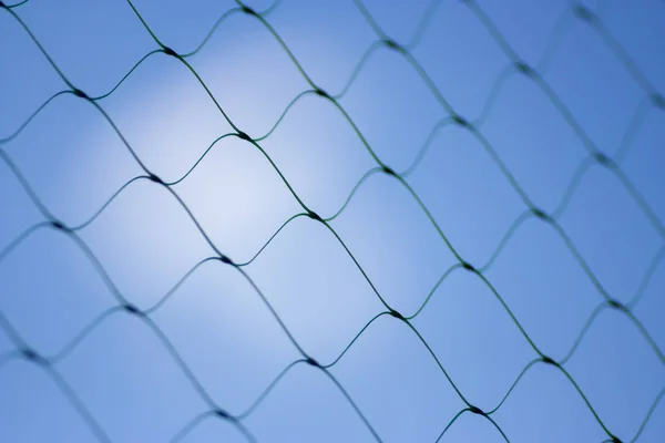 Fence on a blue sky with cloud, Mesh fence with partly cloudy sky, Chain link fence and a blue sky, fence and Blue sky background beyond. Soft focus.