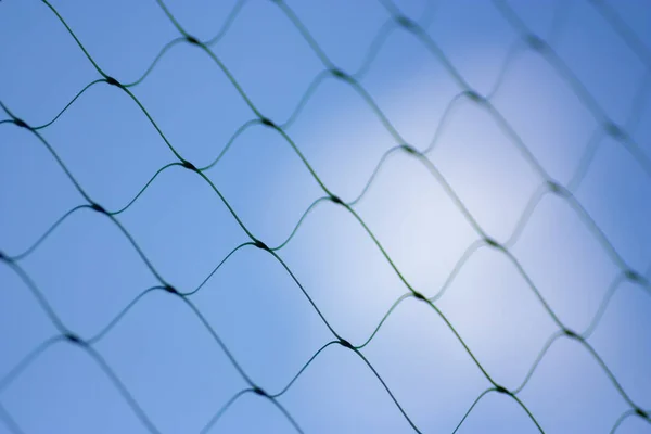 Fence on a blue sky with cloud, Mesh fence with partly cloudy sky, Chain link fence and a blue sky, fence and Blue sky background beyond. Soft focus.