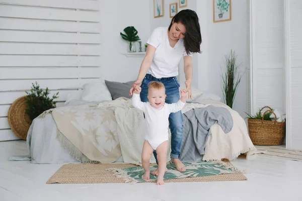 寝室で母親の助けを借りて歩くことを学ぶ幸せな小さな赤ちゃん — ストック写真