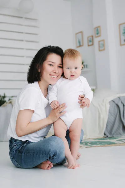 彼女の小さな混合人種の赤ちゃんと幸せな若いアジアの母親のホームポートレート。1歳の赤ちゃん. — ストック写真