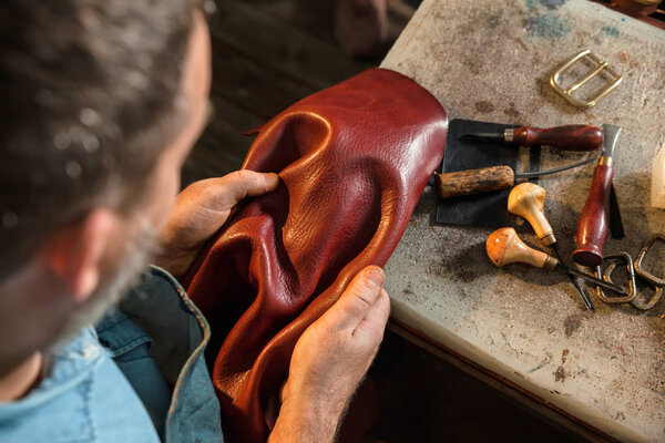 Craftsman touching leather, close-up. A raw material, stuffs and preparation of leather craft work